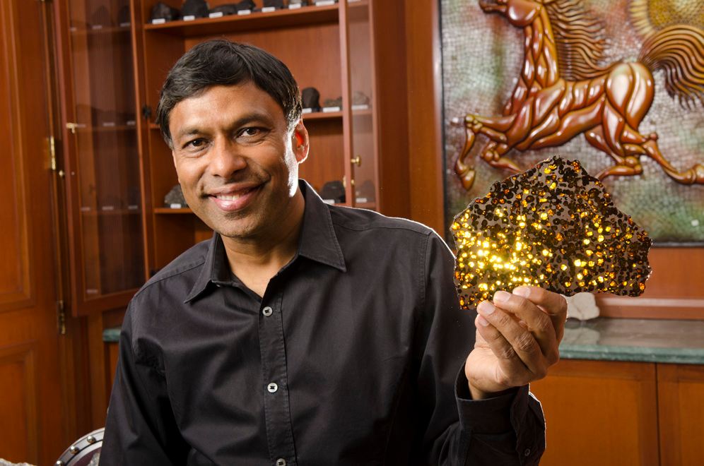 Naveen-Jain[1]陨石的人：耆那教持从溢达的石陨石的抛光片，阿根廷。它的注入一个琥珀.jpg